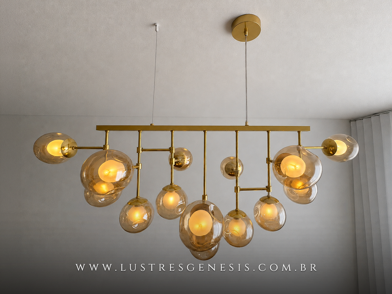 Vista lateral do Lustre Pendente Jabuticaba dourado com iluminação quente e globos de vidro âmbar, instalado em sala de jantar contemporânea com mesa de madeira e cortinas claras.